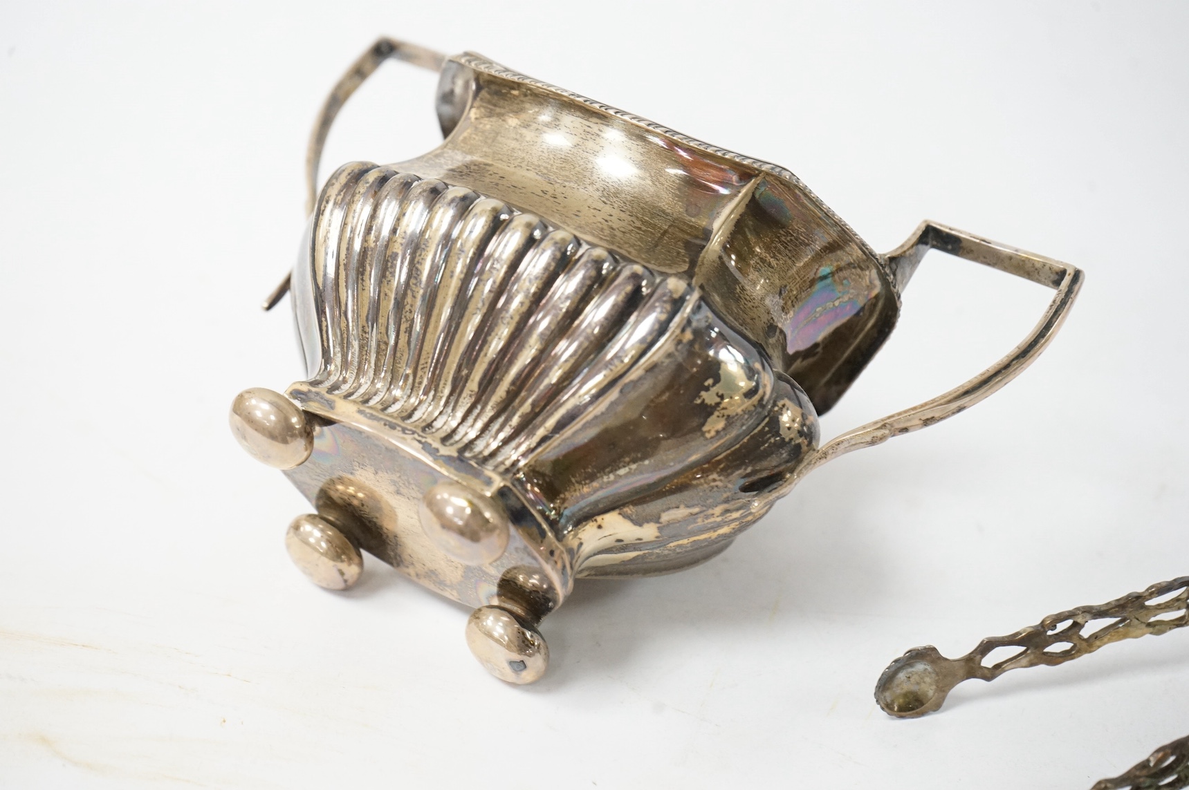 An Edwardian demi fluted silver two handled sugar bowl, Birmingham 1901, together with a pair of silver sugar tongs and a small silver dish, 7.1oz. Condition - fair